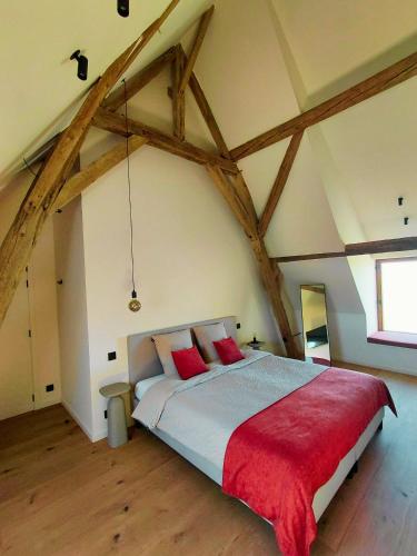 a bedroom with a large bed with red pillows at Hoeve De Hemel in Zuienkerke