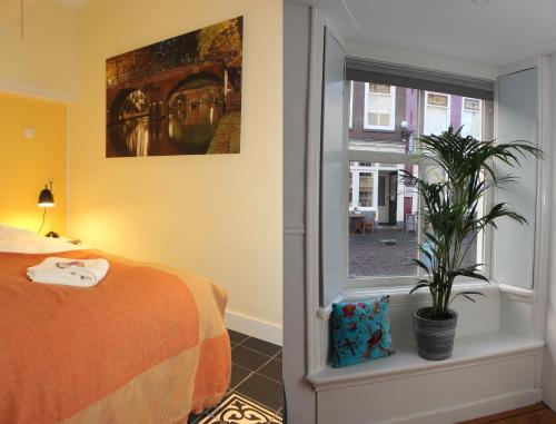 a bedroom with a bed and a plant next to a window at De Verrassing in Utrecht