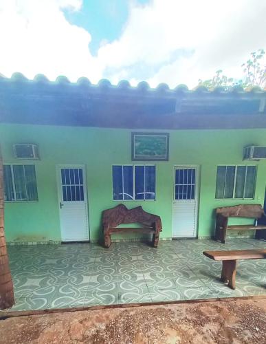 a green building with two benches and windows at Pousada são Martins in Estivado