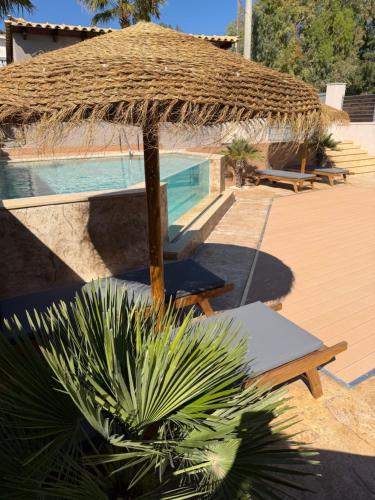a resort with a pool and a straw umbrella at Jimmy's place in Artemida