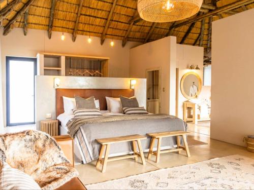 a bedroom with a large bed and a chair at Avenir Safari Group in Okahandja