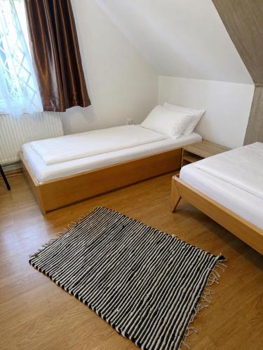 a bedroom with two beds and a rug on the floor at Cabana Ocna Mesaros in Ocna Şugatag