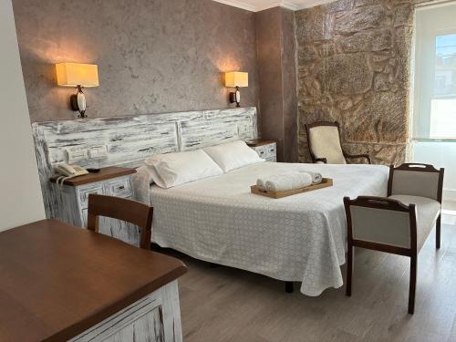 a bedroom with a bed and two chairs and a table at Pensión O Prouso in San Mamede de Carnota