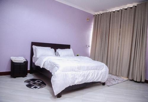 a bedroom with a large bed with white sheets at Jeswel Lux villa in Dodoma