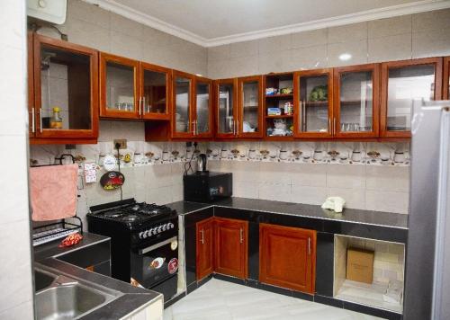 a kitchen with wooden cabinets and a black counter top at Jeswel Lux villa in Dodoma