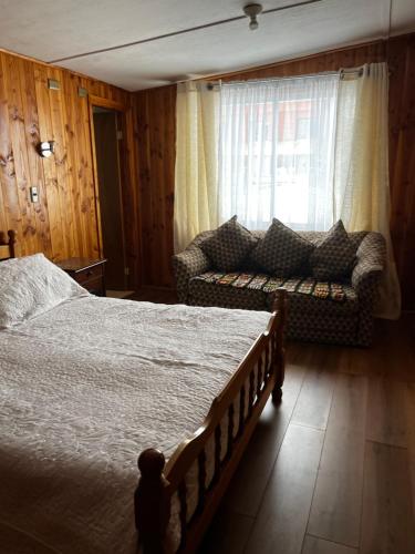 a bedroom with a bed and a couch and a window at Hospedaje Lala in Villarrica