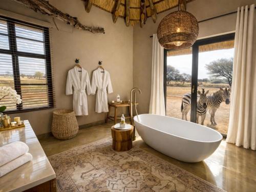 a bathroom with a tub and a zebra in the background at Avenir Safari Group in Okahandja