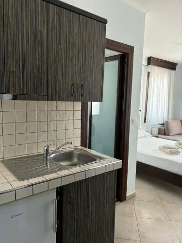 a kitchen with a sink and a room with a bed at Makedos Sea View in Nea Vrasna