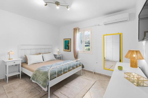 a white bedroom with a bed and a mirror at Antigone's Blue Vista in Kampos Paros