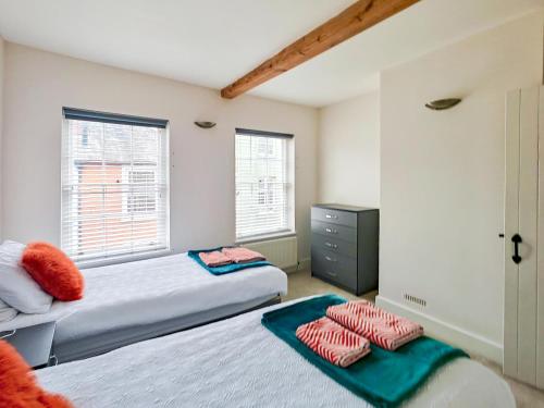 a bedroom with two beds and a dresser and two windows at 4 Bed in Lymington oc-c41423 in Lymington