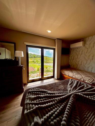 a bedroom with a large bed and a large window at Quinta Santo Antonio in Gouveia