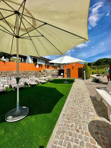 a patio with a large umbrella and white chairs at Quinta Santo Antonio in Gouveia