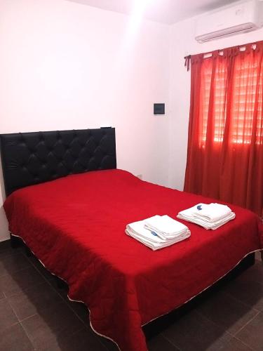 a bedroom with a red bed with two towels on it at El Recodo in La Rioja