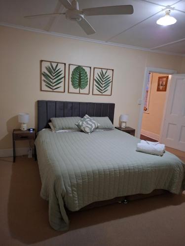 a bed in a bedroom with two pictures on the wall at Woodhill Way Burra in Burra