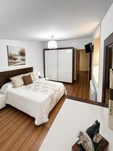 a bedroom with a large white bed and a television at Casa da Xastra in Vimianzo
