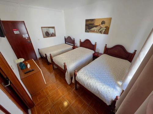 a room with two beds and a wooden floor at Alojamentos Altamira in Formigal