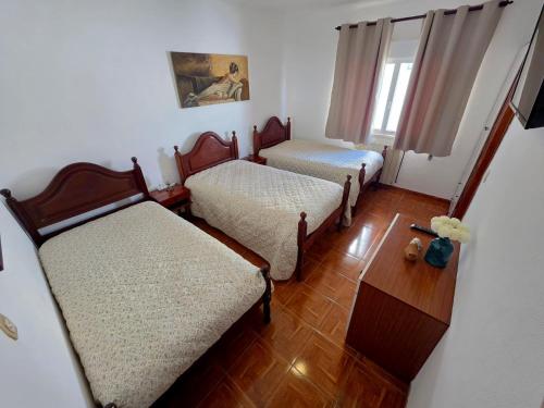 a small room with two beds and a window at Alojamentos Altamira in Formigal