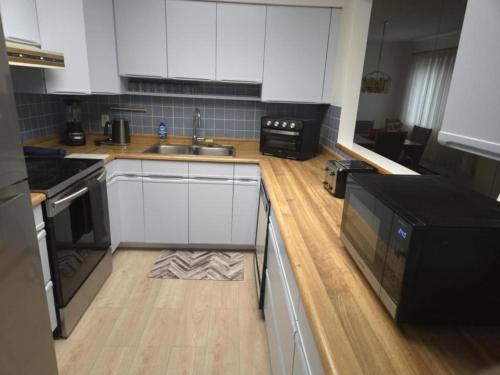 a kitchen with white cabinets and a wooden floor at unique Two -Bedroom Central Townhouse in Vancouver