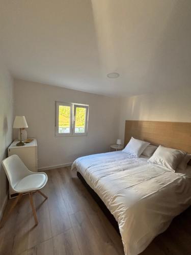 a bedroom with a bed and a chair and a window at Casa papillon in Outeiro