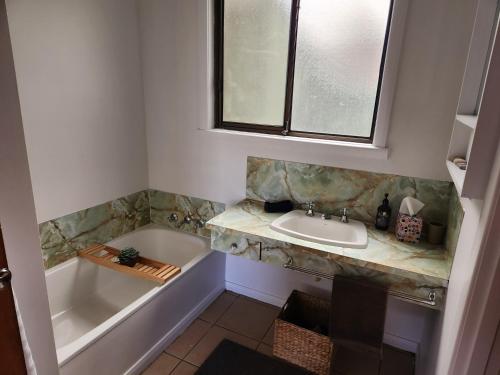 ein Badezimmer mit Badewanne, Waschbecken und Fenster in der Unterkunft Zeehan Affect in Zeehan