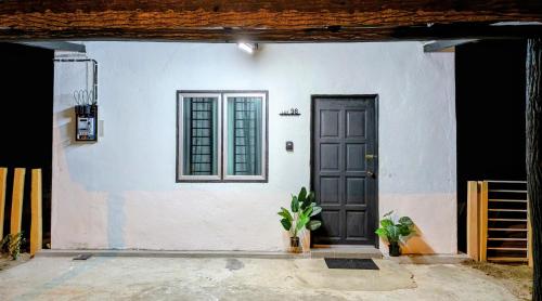 a white house with a black door and a plant at Zulis Haven Stay in Kuala Rompin