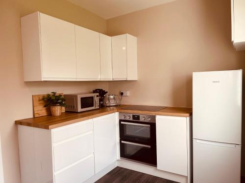 a kitchen with white cabinets and a white refrigerator at West Highland Hideaway in Kinlochleven