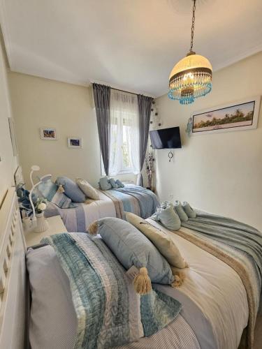 two twin beds in a bedroom with a chandelier at A un paso de Bilbao in Galdakao