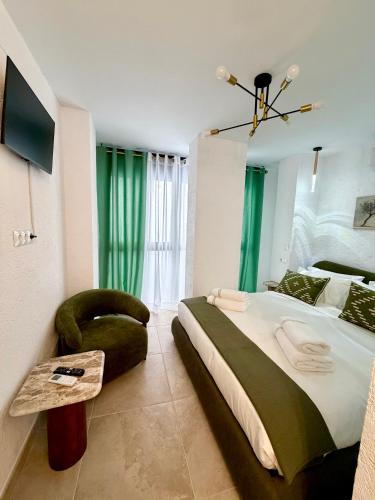 a bedroom with a large bed and a green chair at Casa Natali in Fuengirola