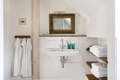 a bathroom with a sink and a mirror and towels at Leuchtturnwohnung in Pommerby