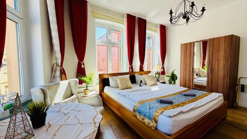 a bedroom with a bed and a couch and windows at FewoZauber "Pension am Dom", Historische Apartments, Superzentral, 7min zum Schloss in Schwerin