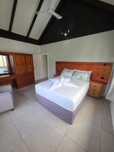 a bedroom with a large bed with a wooden headboard at Savusavu Terraces - Unit 2 in Savusavu