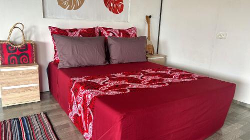 a bed with red sheets and pillows in a room at KOKI Horizon in Atuona