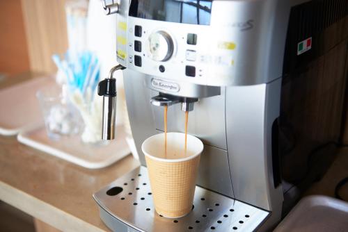 eine Kaffeemaschine mit einer Tasse auf der Theke in der Unterkunft Hotel Select Inn Sano-Ekimae in Sano