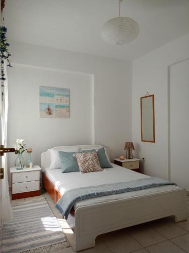 a white bedroom with a bed and a mirror at NiK Seaview Suite Balcony Steps from Beach in Flogita