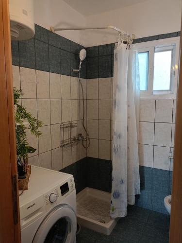 a washing machine in a bathroom with a shower at NiK Seaview Suite Balcony Steps from Beach in Flogita