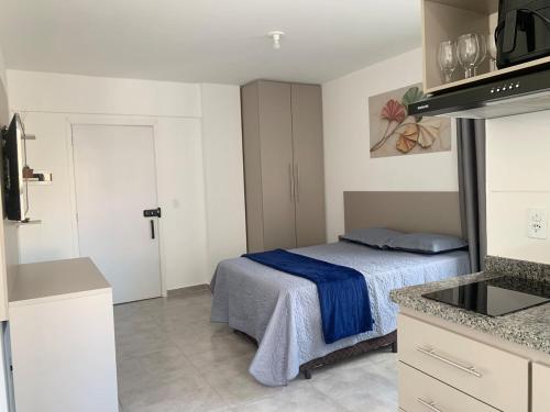 a small bedroom with a bed and a kitchen at Studio moderno com cozinha completa e Wi-Fi centro in Barbacena