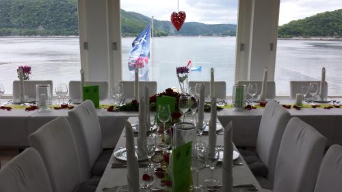 a table with white chairs and a view of the water at Strandhaus Edersee Nr 12 - Kaminzimmer, Seeblick, Badestrand, Seeterrasse in Waldeck