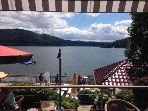 a view of a lake with people on a dock at Strandhaus Edersee Nr 12 - Kaminzimmer, Seeblick, Badestrand, Seeterrasse in Waldeck