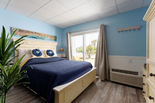 a bedroom with a bed with blue walls and a window at Co Sea Casa in Carolina Beach