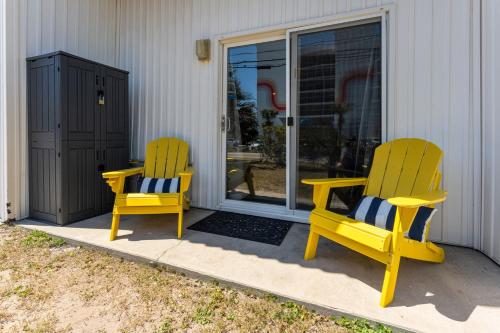 two yellow chairs sitting on the front porch of a house at Co Sea Casa in Carolina Beach