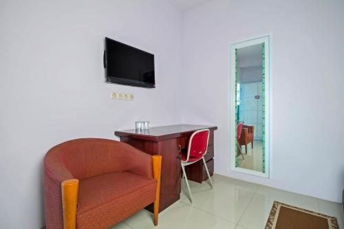 Habitación con escritorio, silla y TV. en RedDoorz Plus @ Guntur Raya Setiabudi en Yakarta