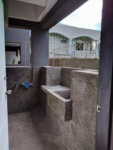 an outdoor shower with a stone wall with a sink at Anabelle Residence in Dumaguete