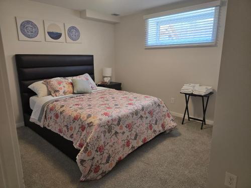 a bedroom with a bed with a floral bedspread and a window at The Peaceful Lower Loft in Winnipeg