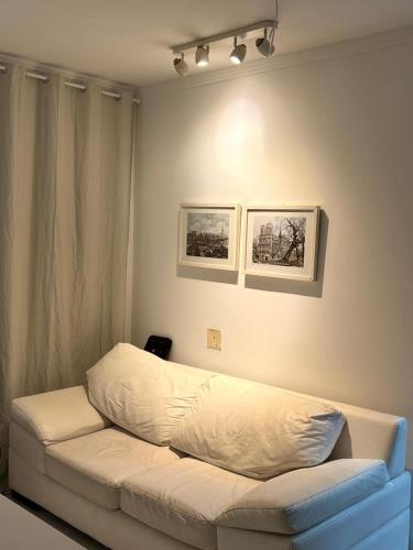 a white couch in a room with two pictures on the wall at Apartamento com 02 quartos in Maceió