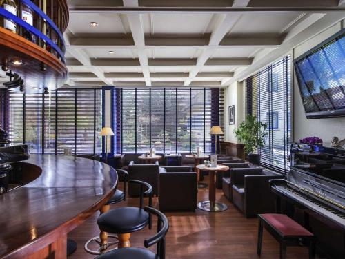 a bar with chairs and a piano in a room with windows at Offenburg City Hotel by Belvilla in Offenburg