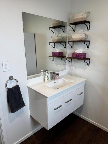 a white bathroom with a sink and a mirror at Denbigh Homestay in Midhirst
