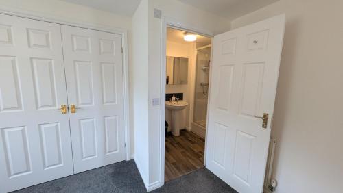 a hallway with two white doors and a bathroom at Large Modern House With Private Parking in Heeley