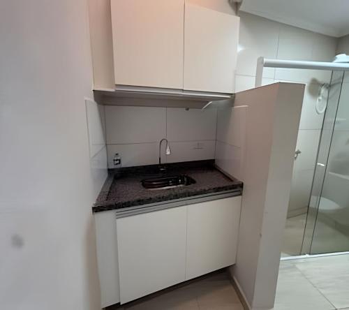 a small kitchen with white cabinets and a sink at Katie Studio Prime Hotel Extrema MG + breakfast in Extrema