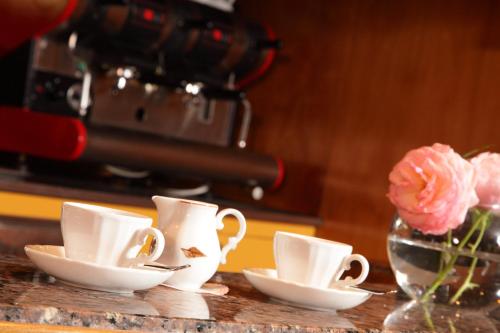 a table with three cups and a vase with flowers at Hotel Abbazia in Grado