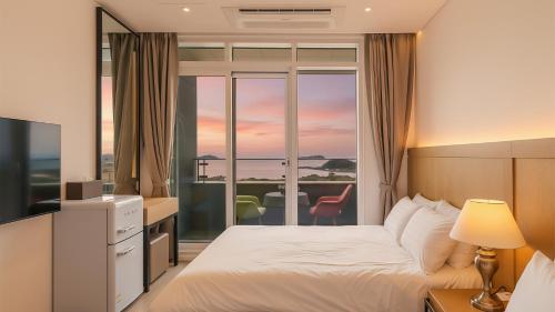 a hotel room with a bed and a view of the ocean at Goseong Moneblue Pension in Goseong